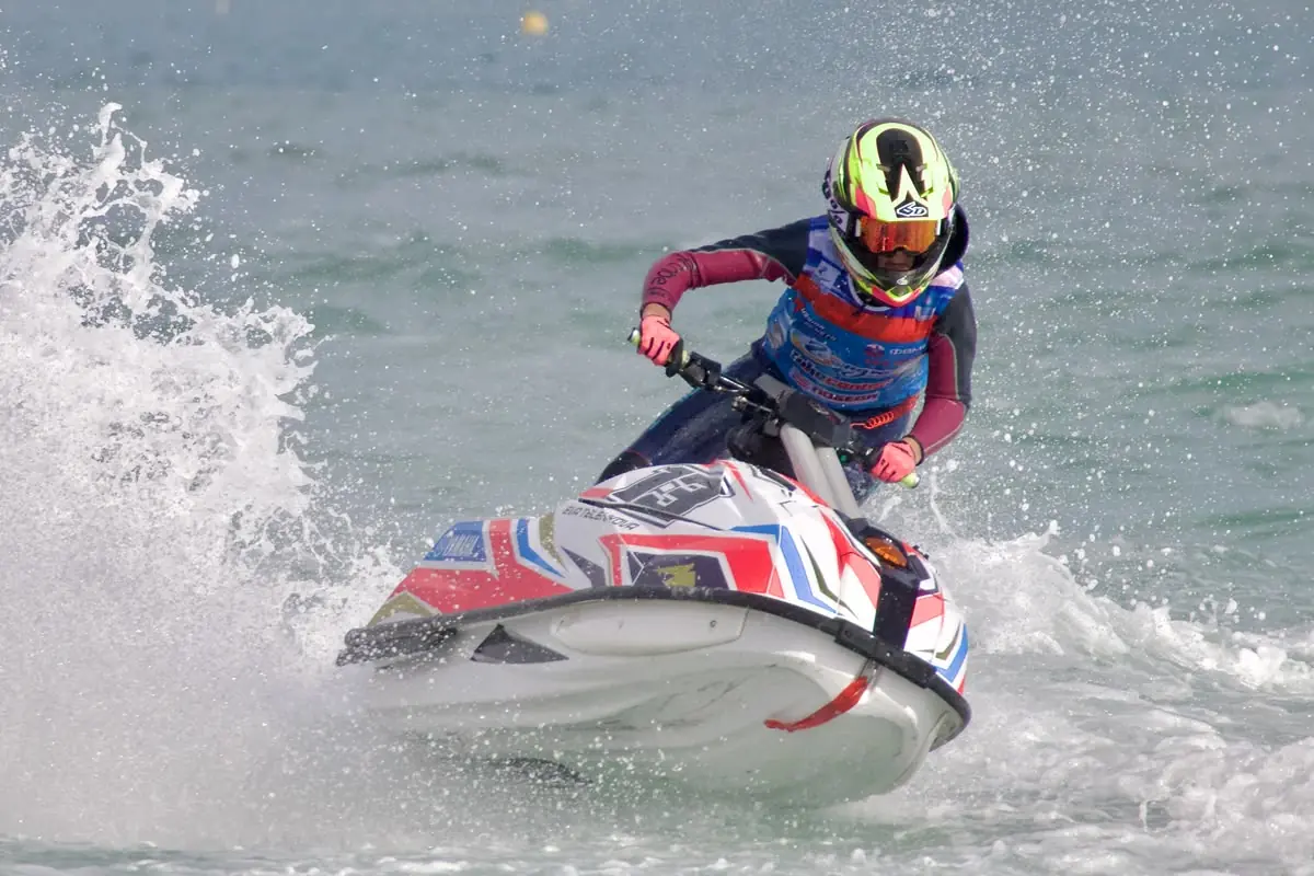 Eva takes a turn on an aquabike through a wall of spray